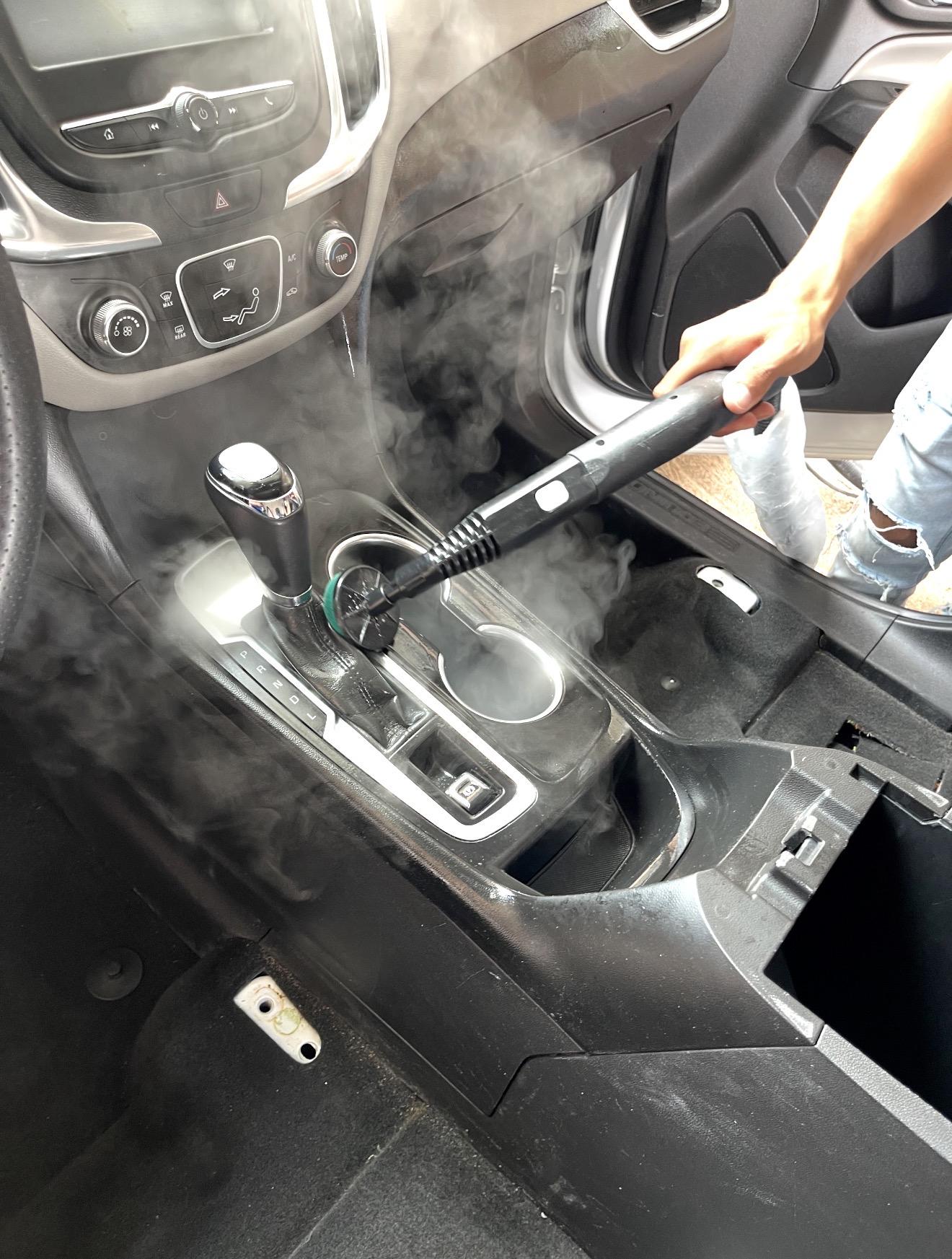 Limpieza a vapor del interior de un automóvil, enfocada en la consola central.